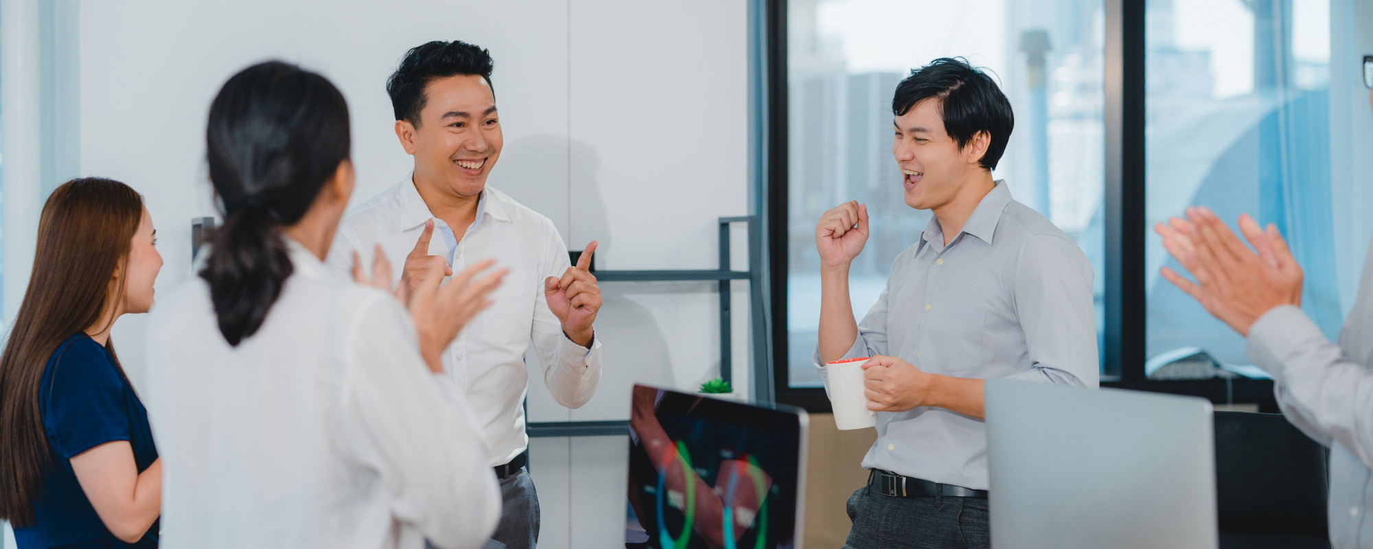 Millennial group young businesspeople asia businessman businesswoman celebrate giving five after dealing feeling happy signing contract agreement meeting room small modern office